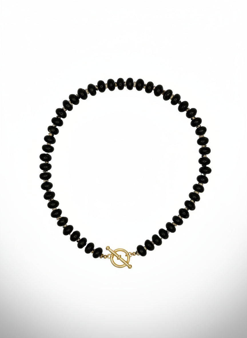 Black beaded necklace with a gold clasp on a light gray background